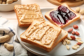 Delicious toasts with peanut butter, jam and nuts on table, closeup