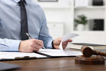Lawyer working with documents at wooden table in office, closeup