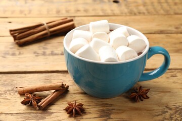 Tasty hot chocolate with marshmallows and spices on wooden table, closeup