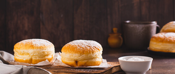 Sweet donuts with powdered sugar filled with boiled condensed milk on a plate web banner