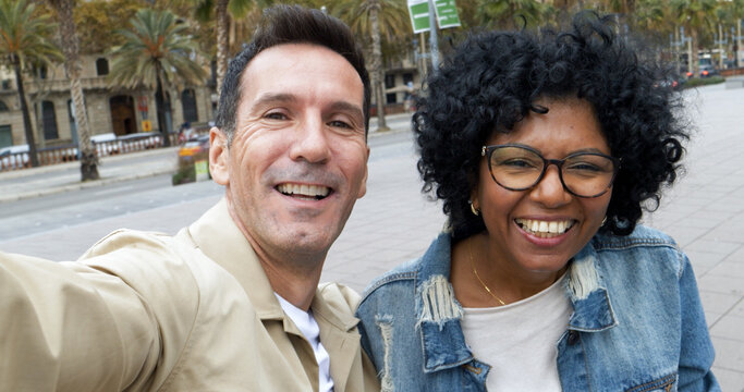 Selfie perspective of a diverse middle-aged tourist couple taking a selfie in a city. Heterosexual couple on vacation