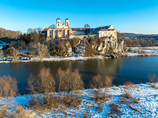 Tyniec near Krakow, Poland. Benedictine abbey, monastery and church on the rocky cliff and Vistula river. Aerial view at sunset in winter with snow and trees - 715013727