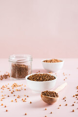 Dry buckwheat tea granules in a bowl, spoon and jar on the table vertical view