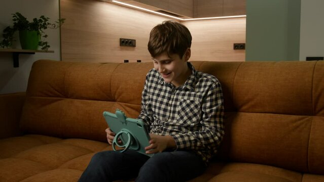 Discover a cozy world of exploration as an autistic kid engages with a tablet on the couch. A glimpse into embracing technology for comfort and learning