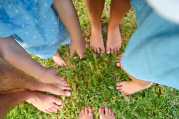 Happy young family spending time outdoor on a summer day. Feet on the grass