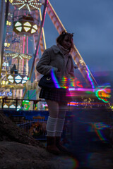 young cosplay woman on fun fare and Ferris wheel with magic winter lights