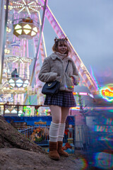 young cosplay woman on fun fare and Ferris wheel with magic winter lights