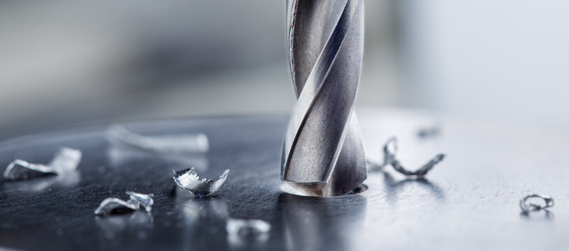 metal drill bit make holes in steel billet on industrial drilling machine