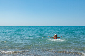 Fototapeta na wymiar Festive Beach Waves: Girl in Red Swimsuit and Santa Hat