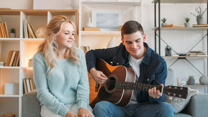 Musical date. Romantic hobby. Happy man playing acoustic guitar for cheerful woman family enjoying...
