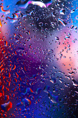 colorful light and water drops on glass, breathtaking view created by light and water. Macro photography. Blurry focus.