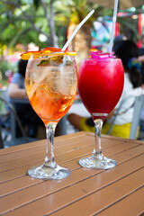 young red and rosatto cocktail glasses on bistro table in public square below trees
