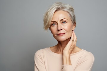 portrait of a beautiful woman 50 years old with natural makeup in a beige T-shirt on a neutral background. The concept of natural beauty and anti-age care