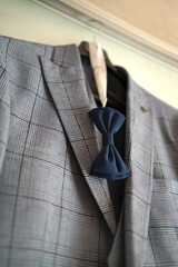 Gray formal jacket and bow tie on hanger.