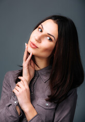 Fototapeta premium Woman Posing for Picture With Hand on Chin. A woman striking a pose, with her hand resting gently on her chin, as she smiles for the camera.