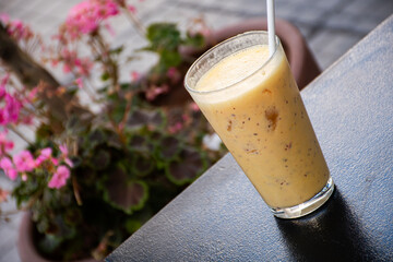 orange pineapple smoothie with refreshing crushed ice on a hot day with blurred flowerbed in the...