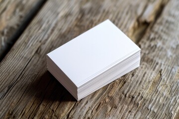 A stack of white business cards placed on top of a wooden table. Perfect for showcasing professional and corporate branding. - obrazy, fototapety, plakaty