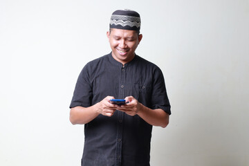 Moslem Asian man smiling happy when texting using his mobile phone