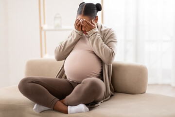 Young black pregnant woman feeling sad and crying at home