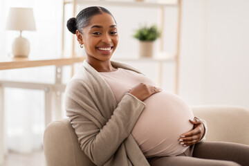 Side view of african american expecting lady sitting on couch