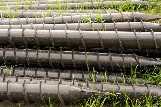 Screw piles for terrace foundations. Geo screws are steel round elements of an engineering structure. Industrial maintenance of metal tools for architectural construction work.