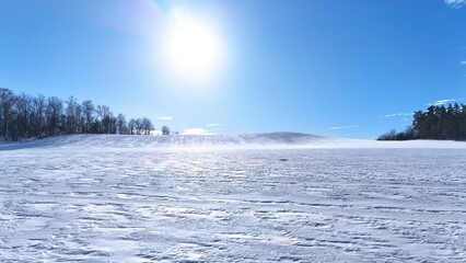 Krajobraz zimowy, śnieg na stoku górskim, drzewa, zdjęcie zrobione pod słońcem.