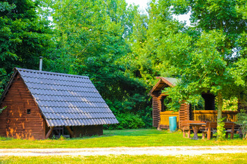 Beautiful brown wooden huts and wooden benches in the forest.