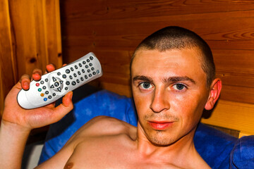Man in wooden house on couch with remote control in Germany.