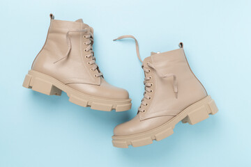 Beige trendy boots on color background, top view.