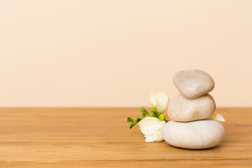 Fototapeta na wymiar Spa stones with freesia flower on wooden table
