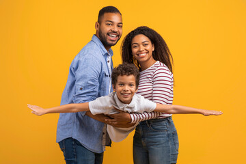 Family bonding. Joyful black man and woman holding their son on hands