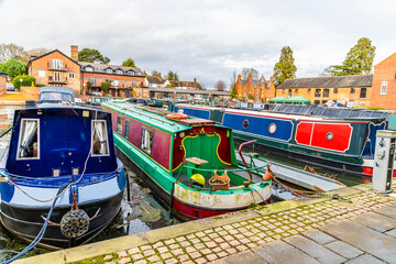 Fototapeta na wymiar A view past canal boats at the canal basin on the frozen Grand Union canal in Market Harborough in Winter