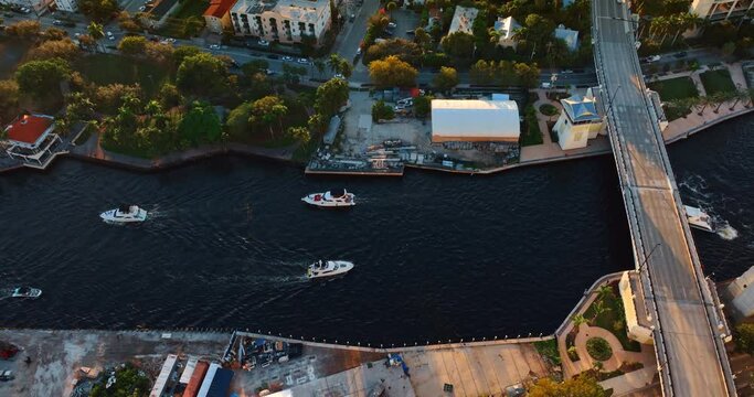 Four boat move slowly by the river near the bridge. Drone approaching one of the vehicles in Miami, Florida, USA.