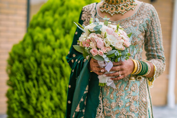 Indian bride's holding beautiful wedding flowers bouquet close up