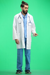 The male doctor, full-length, on a green background, points to the side