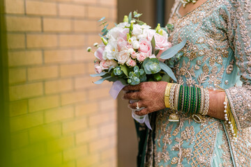 Indian bride's holding beautiful wedding flowers bouquet close up