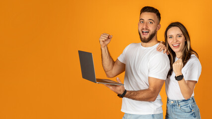Happy confident young european man and woman winners in casual use laptop