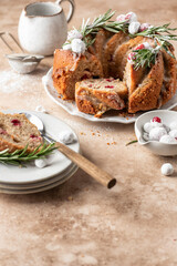 Christmas bundt cake decorated with glaze, cranberries and rosemary served on beige table with text space. Homemade cake recipe