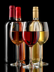 Red, white and rose wine glasses and bottles on black background - 715095327