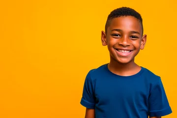 Meubelstickers Portrait of a smiling African little boy in a blue t-shirt on yellow background. Front view, happy child in a blue shirt. © Vero