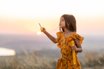 Beautiful little girl of Indian appearance at sunset in summer, long hair,