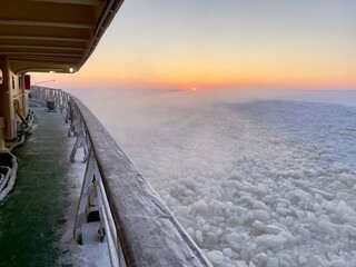 Icebreaker boat breaks the frozen sea at sunset, Sweden 