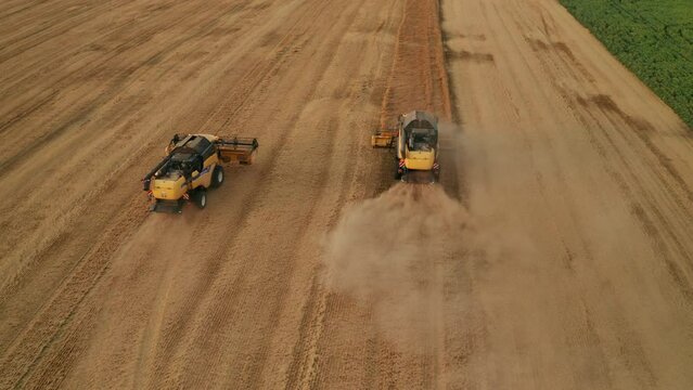 BERLIN , GERMANY - JULY 15 2023: Powerful combine harvesters work in wheat field bird eye view. Modern agricultural machines reap ripe rye driving across plantation