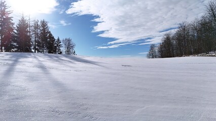  Krajobraz zimowy, śnieg na stoku górskim, drzewa, zdjęcie zrobione pod słońcem.