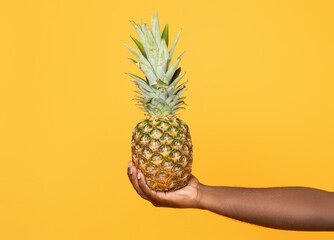 Cropped shot of black young man holding pineapple in hand