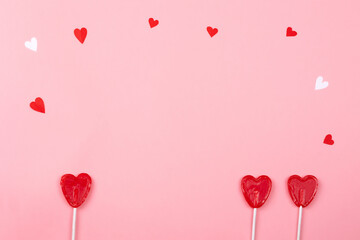 three heart-shaped lollipops on light pink background, love concept, couple together, love triangle, Valentine's day celebration