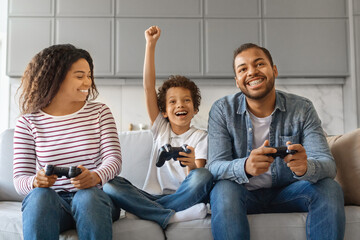 Family Pastime. Cheerful Black Parents Playing Video Games With Son At Home - obrazy, fototapety, plakaty