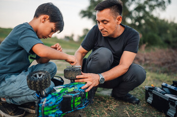 Father is teaching a son how to fix broken car on a remote control car