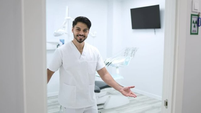 Male dentist opens the door and invites an unrecognisable patient into a dental clinic. Male dentist welcoming an unrecognisable patient into the medical office of a modern dental clinic.
