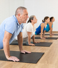 People of different ages performing cobra exercise during group Pilates workout. Active lifestyle and wellness concept